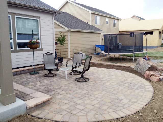 This backyard patio in Berthoud, CO, is constructed with beautiful Bogert pavers, and accented with small flagstone walls. Natural boulders were used to create the backyard planter.