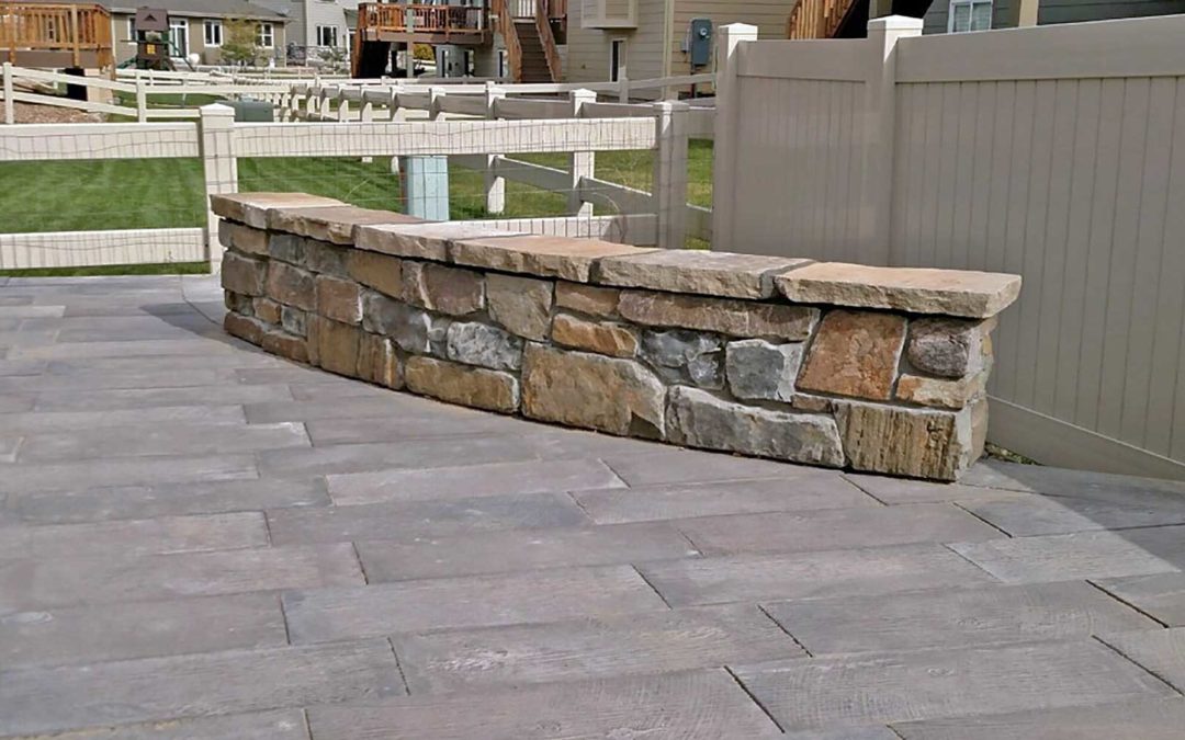 A finished outdoor living area with landscaping featuring a cobble veneer bench seat in Frederick, CO by SR Custom Stone of Longmont