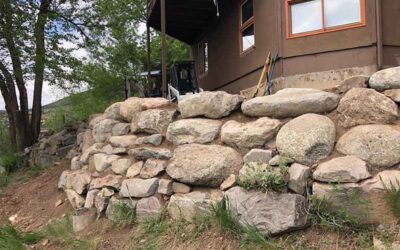 Boulder retaining wall with red flagstone yard treatment in Lyons